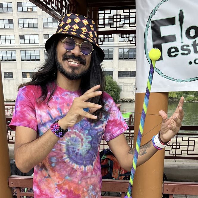 Mustafa smiling in a tie-dye shirt holding a Derp Gear wand